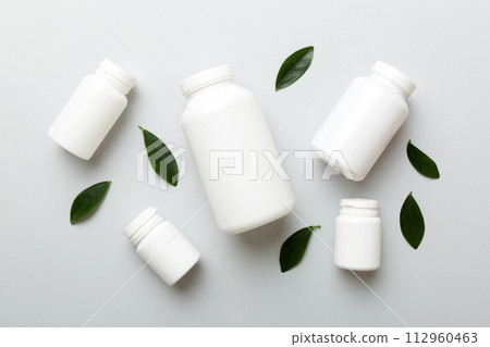 supplement pills with medicine bottle health care and medical top view. Vitamin tablets. Top view mockup bottle for pills and vitamins with green leaves, natural organic bio supplement, copy space 112960463