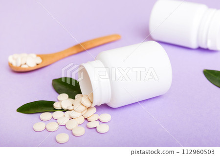 different drugs and health supplement pills poured from a medicine bottle health care and medical top view on colored background 112960503