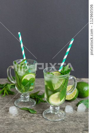 Mojito cocktail. Refreshing mojito cocktail with lime, lemon and mint in a tall glass with a stick Mojito cocktail. Refreshing mojito cocktail with lime, lemon and mint in a tall glass with a stick 112960506