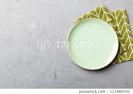 Top view on colored background empty round green plate on tablecloth for food. Empty dish on napkin with space for your design 112960593