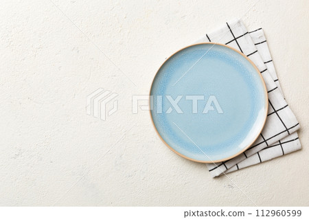 Top view on colored background empty round blue plate on tablecloth for food. Empty dish on napkin with space for your design 112960599