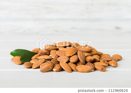 Close-up of Almonds nuts with leaves on table background. Top view. Flat lay 112960620
