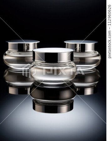 AI-generated content. 3 similar luxury glossy silver glass jars with cosmetic product stand on black background, vertical photo, close-up. 112960626