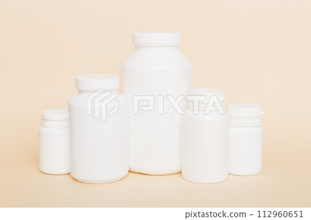 supplement pills with medicine bottle health care and medical top view. Vitamin tablets. Top view mockup bottle for pills and vitamins with green leaves, natural organic bio supplement, copy space 112960651