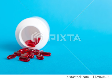 Red pills spilled around a pill bottle. Medicines and prescription pills flat lay background. Red medical capsules 112960698