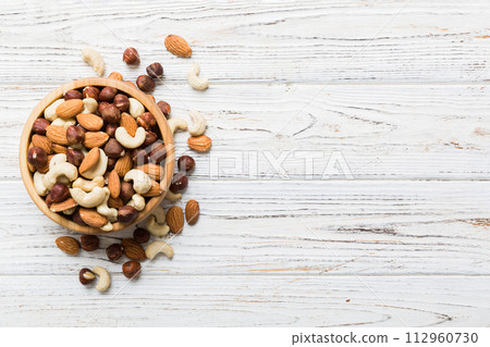 Assortment of nuts in wooden bowl on colored table. Cashew, hazelnuts, walnuts, almonds. Mix of nuts Top view with copy space Assortment of nuts in wooden bowl on colored table. Cashew, hazelnuts, walnuts, almonds. Mix of nuts Top view with copy space 112960730