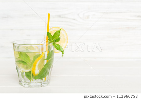 Mojito cocktail. Refreshing mojito cocktail with lime, lemon and mint in a tall glass with a stick Mojito cocktail. Refreshing mojito cocktail with lime, lemon and mint in a tall glass with a stick 112960758