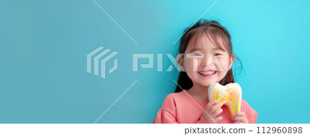 Cute girl holding in hand model of tooth. Dental hygiene and medical health care concept. Cute girl holding in hand model of tooth. Dental hygiene and medical health care concept. 112960898