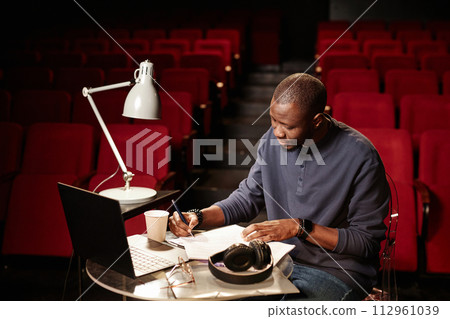 High angle portrait of theater director reading script at table in audience copy space 112961039