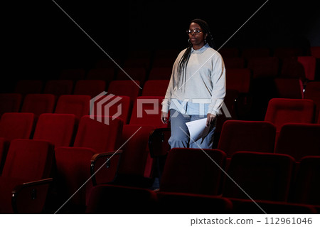 Dramatic portrait of female artist walking towards stage in empty theater audience with low light copy space Dramatic portrait of female artist walking towards stage in empty theater audience with low light copy space 112961046
