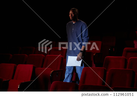 Portrait of Black man walking towards stage in empty theater audience copy space 112961051