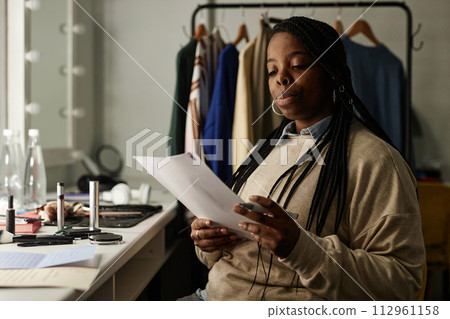 Portrait of African American woman reading lines preparing for performance in dressing room copy space Portrait of African American woman reading lines preparing for performance in dressing room copy space 112961158