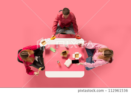 Creative collage. Group of people, friends sitting at Asian cafe and eating delicious food while speaking against pink background. Creative collage. Group of people, friends sitting at Asian cafe and eating delicious food while speaking against pink background. 112961536