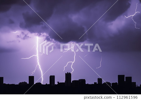Ray. Lightning. Electric storm. Strong electrical storm with lots of lightning and thunder. Electrical storm over fields. Lightning photography. Silhouette of buildings and trees. 112961596