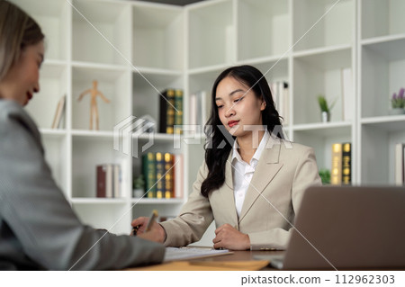 Lawyers woman and businesswoman discussing contract papers sitting at the table. Concepts of law, advice, legal service Lawyers woman and businesswoman discussing contract papers sitting at the table. Concepts of law, advice, legal service 112962303