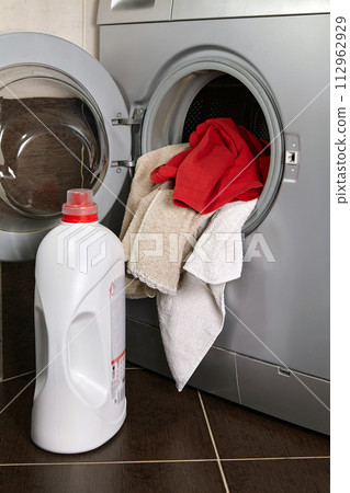 Placing laundry in the washing machine in the laundry room Placing laundry in the washing machine in the laundry room 112962929