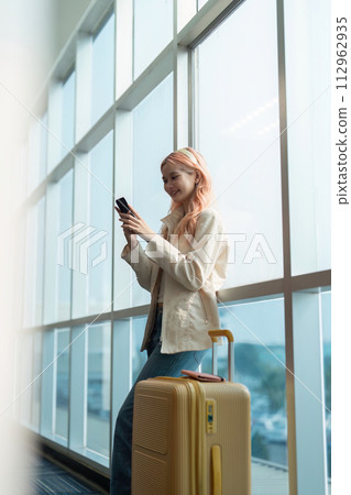 Traveler woman asian in airport and luggage for vacation, smile and talking on the phone check boarding ticket. Female traveler with suitcase, international and departure with passport and trip 112962935
