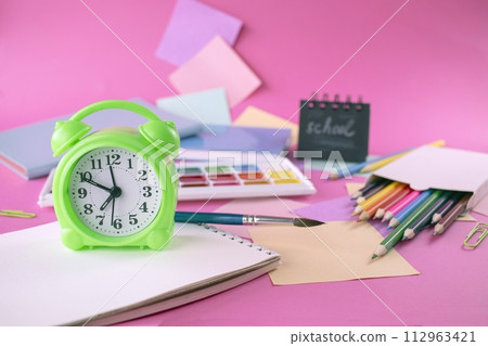 Back to school concept with colored pencils, stickers, alarm clock and notepad on pink background 112963421