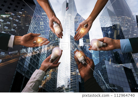 Teamwork and brainstorming concept with businessmen that share an idea with a lamp Teamwork and brainstorming concept with businessmen that share an idea with a lamp 112964740