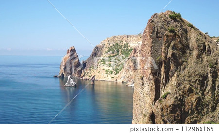 aerial view on calm azure sea and volcanic rocky shores. Small waves on water surface in motion blur. Nature summer ocean sea beach background. Nobody. Holiday, vacation and travel concept aerial view on calm azure sea and volcanic rocky shores. Small waves on water surface in motion blur. Nature summer ocean sea beach background. Nobody. Holiday, vacation and travel concept 112966165