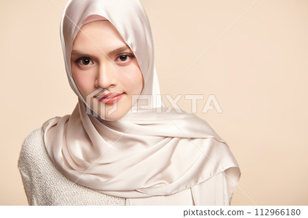 Beautiful young asian muslim woman wearing a white hijab on beige background, Portrait of Arab Beauty. Beautiful young asian muslim woman wearing a white hijab on beige background, Portrait of Arab Beauty. 112966180