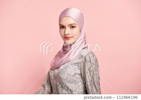Beautiful young asian muslim woman wearing a pink hijab on pink background, Portrait of Arab Beauty. 112966196