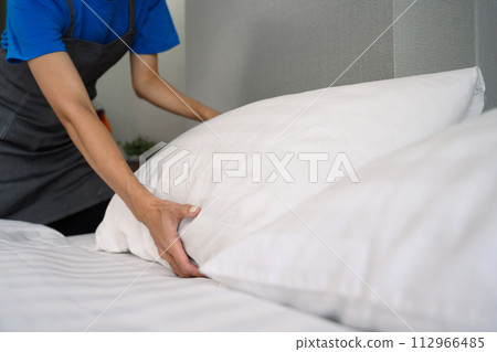 Young woman making bed at home or in hotel room. Housekeeping and cleaning service concept 112966485
