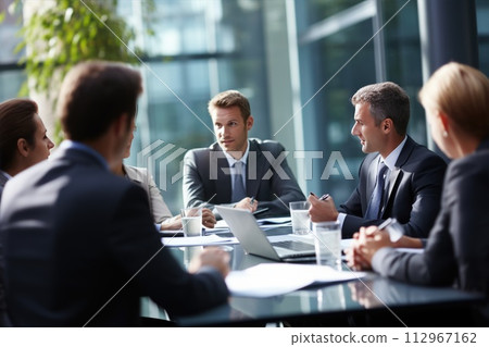 A group of business people are sitting around a table having a meeting A group of business people are sitting around a table having a meeting 112967162