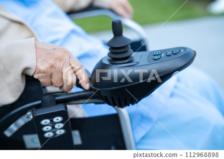 Asian senior woman patient on electric wheelchair with joystick and remote control at hospital. Asian senior woman patient on electric wheelchair with joystick and remote control at hospital. 112968898