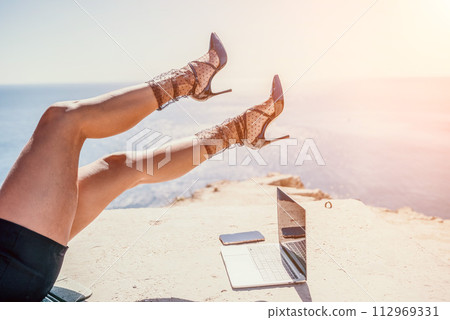 Woman sea laptop. Business woman in yellow hat freelancer with laptop working over blue sea beach. Girl relieves stress from work. Freelance, digital nomad, travel and holidays concept Woman sea laptop. Business woman in yellow hat freelancer with laptop working over blue sea beach. Girl relieves stress from work. Freelance, digital nomad, travel and holidays concept 112969331