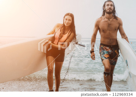 Sea woman and man on sup. Silhouette of happy young woman and man, surfing on SUP board, confident paddling through water surface. Idyllic sunset. Active lifestyle at sea or river. 112969334