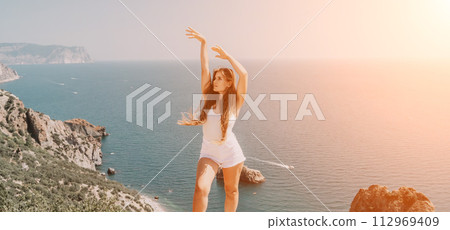Woman summer travel sea. Happy tourist enjoy taking picture outdoors for memories. Woman traveler posing over sea bay surrounded by volcanic mountains, sharing travel adventure journey Woman summer travel sea. Happy tourist enjoy taking picture outdoors for memories. Woman traveler posing over sea bay surrounded by volcanic mountains, sharing travel adventure journey 112969409