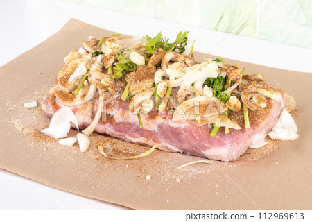 Season meat with onion and garlic cloves, sprinkled with seasonings and salt before baking. 112969613
