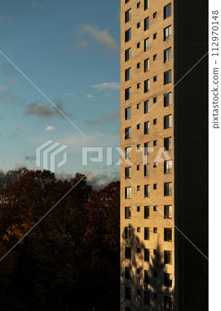 Building in sunset rays with blue sky in the background on a summer evening 112970148