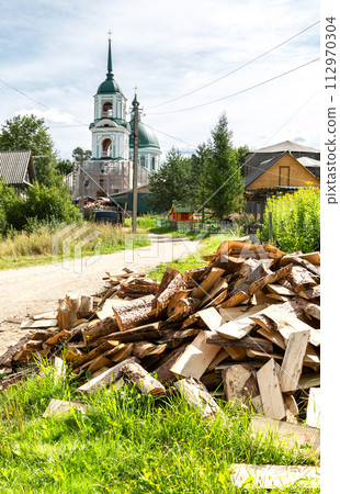 Chopped dry firewood at the countryside against a church 112970304