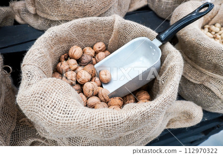 Unpeeled walnuts in a canvas bag are sold in a store Unpeeled walnuts in a canvas bag are sold in a store 112970322