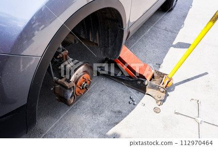 Car without wheel and lift up by jack stand .Waiting for tire replacement Car without wheel and lift up by jack stand .Waiting for tire replacement 112970464