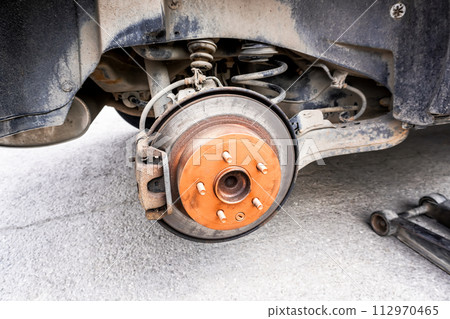An old rusty car brake disc is lubricated with copper grease An old rusty car brake disc is lubricated with copper grease 112970465