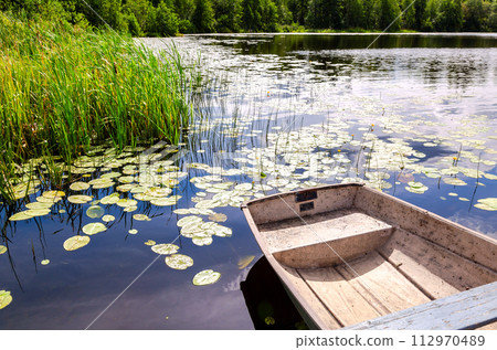 Dirty plastic fishing boat on the bank of the lake in summer 112970489