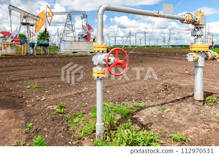 Pipe with control valve against the background pump jack fracking crude oil extraction machine 112970531