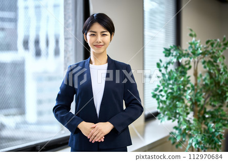 Smiling businesswoman in a suit working in the office Smiling businesswoman in a suit working in the office 112970684