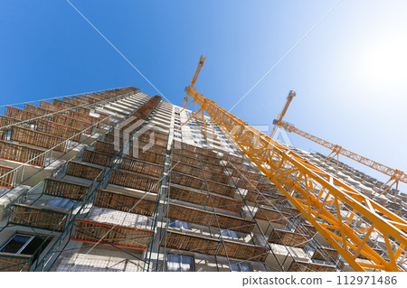 Construction of a multi-storey building using a high-rise yellow crane. Home construction. 112971486