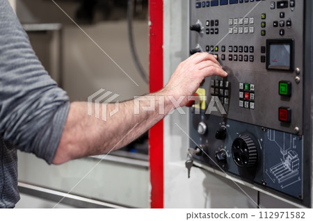 Worker pressing buttons on CNC machine control board in factory. Worker pressing buttons on CNC machine control board in factory. 112971582