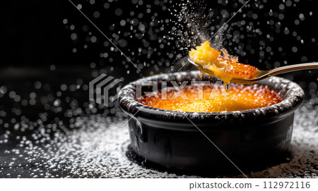 A classic Creme brulee, served in a ramekin, with a spoon breaking through the caramelized surface of the dessert. 112972116