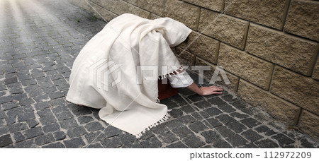 A girl in poor clothes sits on the ground A girl in poor clothes sits on the ground 112972209