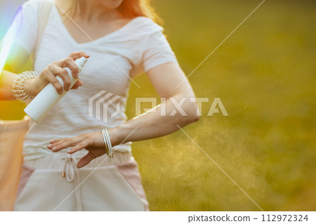Closeup on woman in white shirt applying sunscreen Closeup on woman in white shirt applying sunscreen 112972324