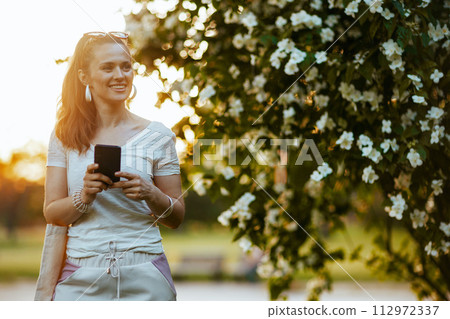 happy modern woman in white shirt using smartphone happy modern woman in white shirt using smartphone 112972337