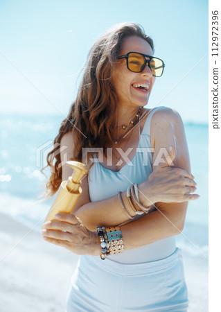 happy elegant woman on beach with spf 112972396