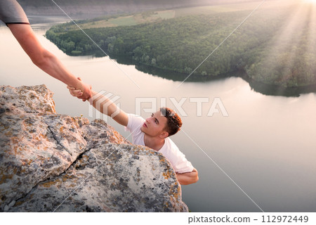 Man help his friend to climb on the rock Man help his friend to climb on the rock 112972449