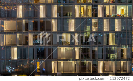 Windows of the multi-storey building of glass and steel lighting inside and moving people within timelapse Windows of the multi-storey building of glass and steel lighting inside and moving people within timelapse 112972472